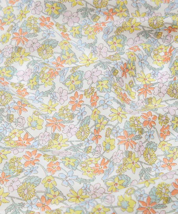 Soft white cotton fabric with pastel floral print in yellow, orange, pink, and blue