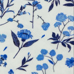 Close-up of white cotton corduroy fabric with blue floral and botanical print pattern