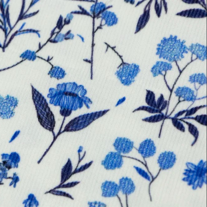 Close-up of white cotton corduroy fabric with blue floral and botanical print pattern