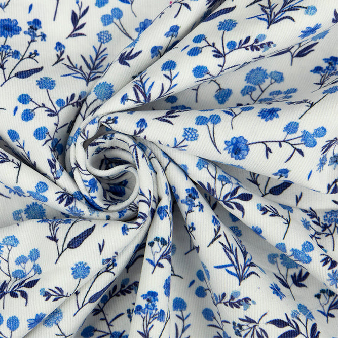 White corduroy fabric with blue floral botanical print, swirled to show texture