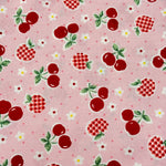 Pink cotton fabric with red cherries, gingham apples, and small white flowers