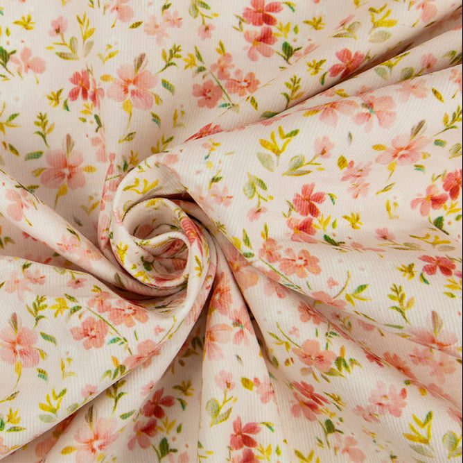 Cream corduroy fabric with scattered pink floral print twisted into a swirl