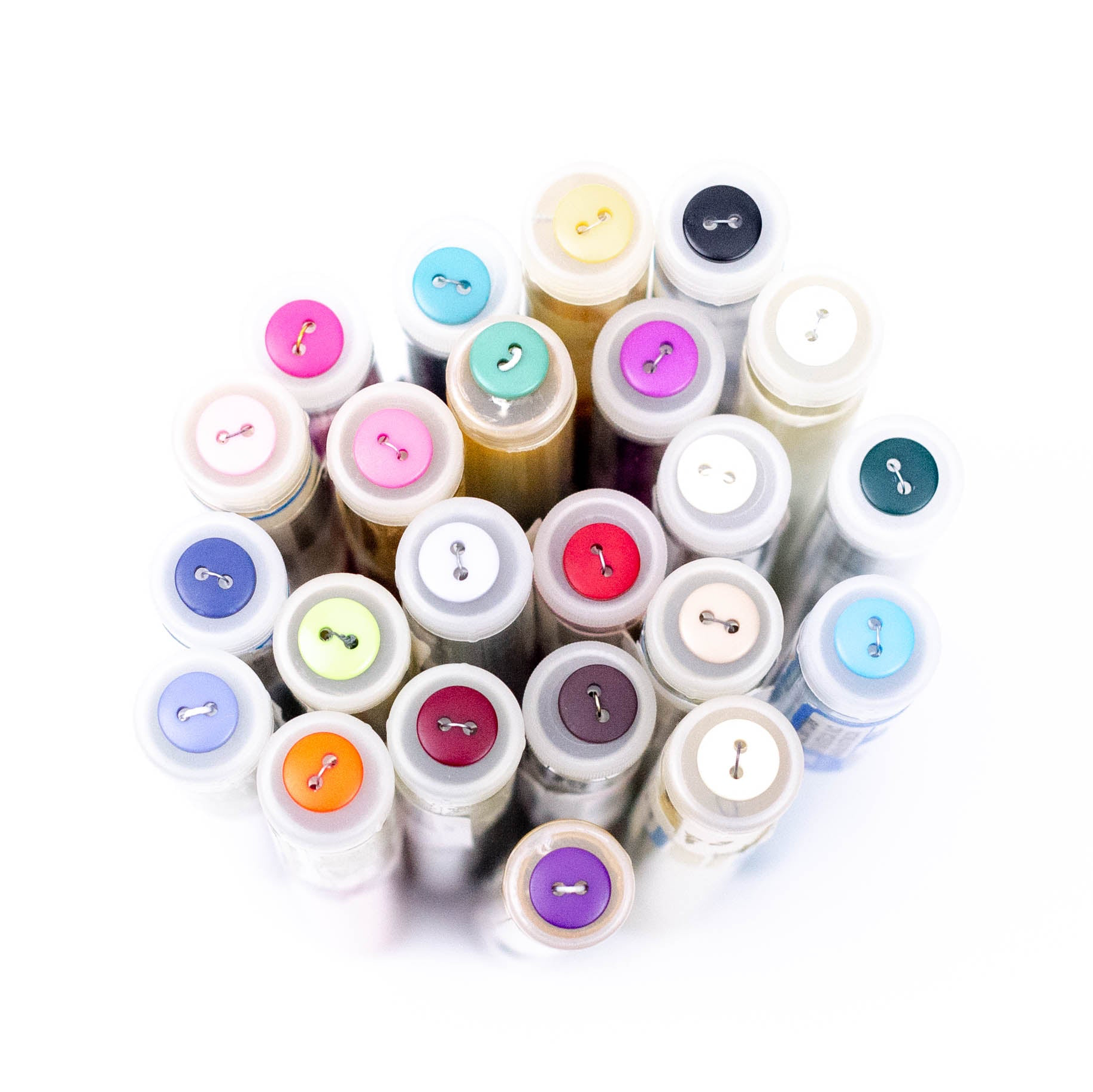 Colorful two-hole plastic buttons displayed on tops of thread spools, multiple colors