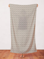 Sage green fabric with small white floral blossoms pattern, held up full length.