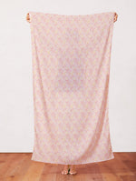 Pink fabric with scattered small colorful Easter ditsy floral print, held up full length.