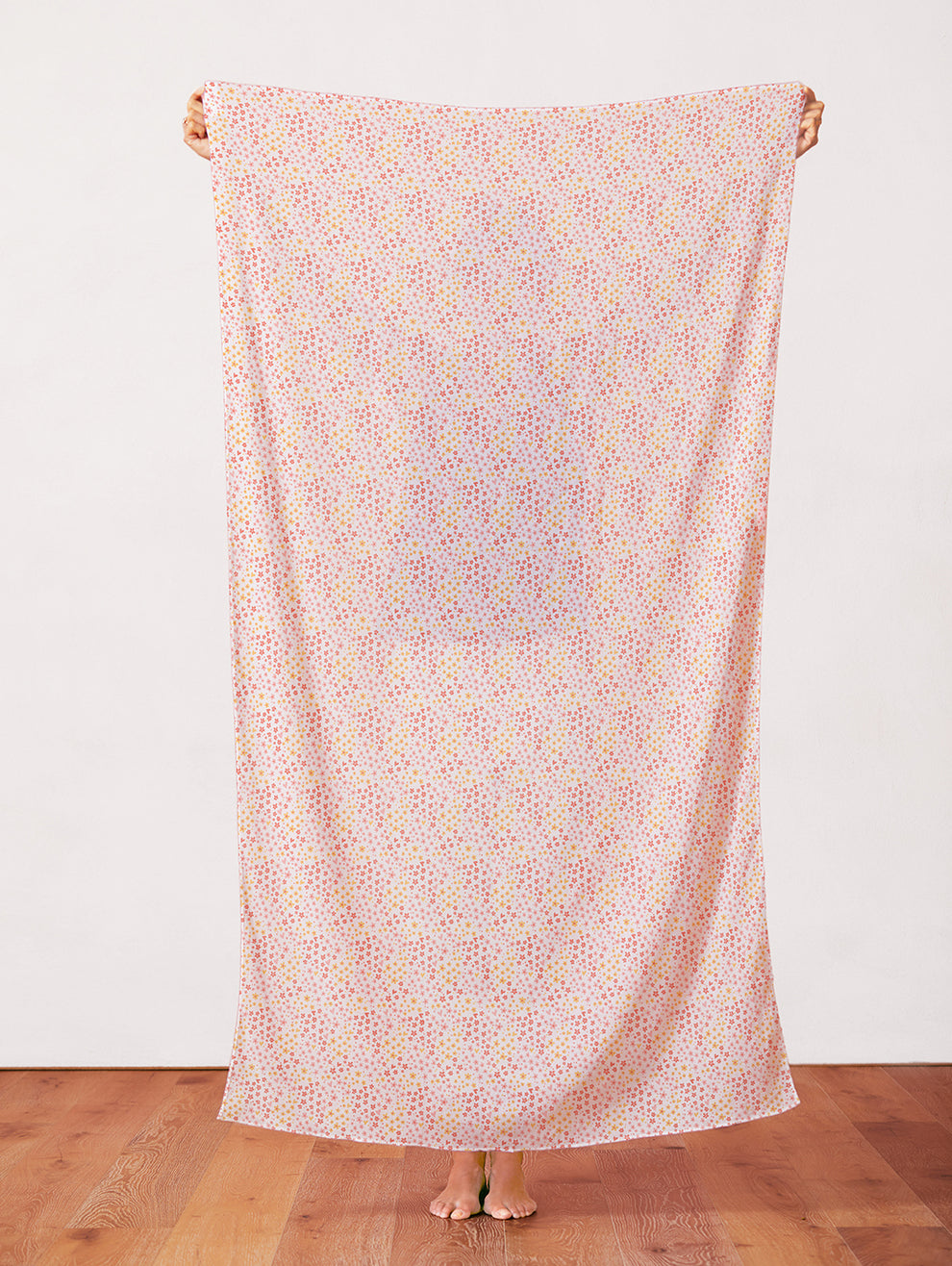 Pink fabric with scattered small colorful Easter ditsy floral print, held up full length.
