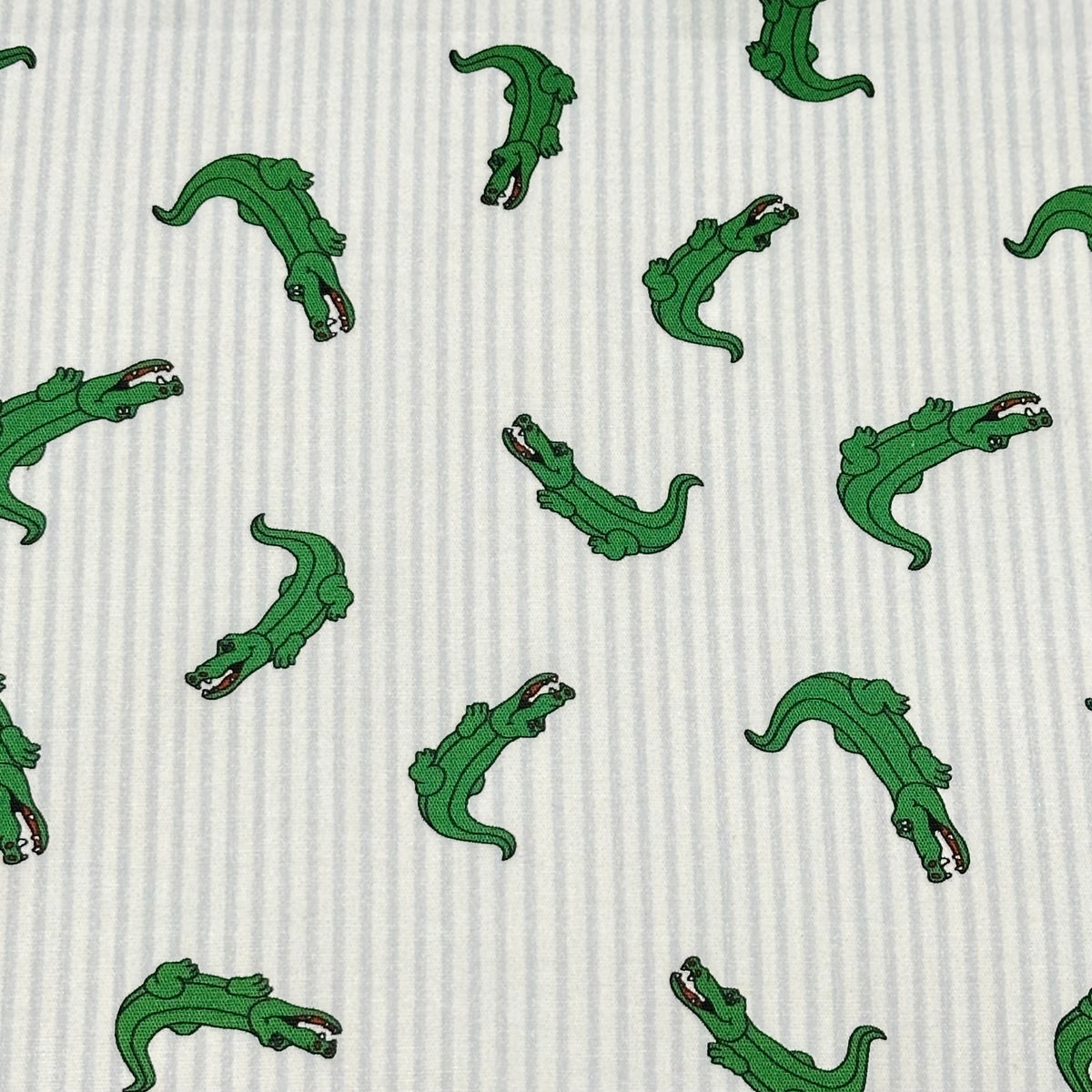 White and light blue striped fabric with scattered green alligator print pattern