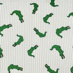 White and blue striped fabric with scattered green cartoon alligator print pattern