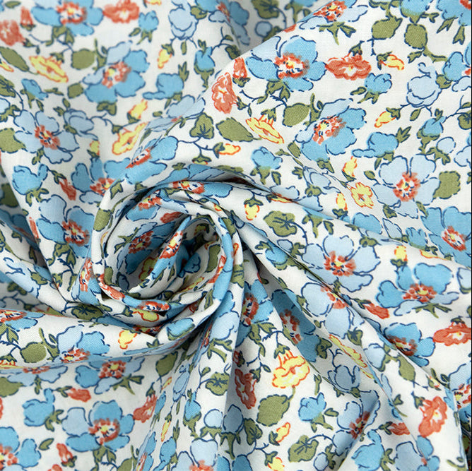 White cotton poplin fabric with blue, rust, and yellow poppy floral print, twisted into a swirl