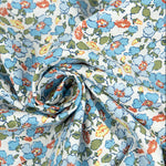 White cotton poplin fabric with blue, rust, and yellow poppy floral print, twisted into a swirl