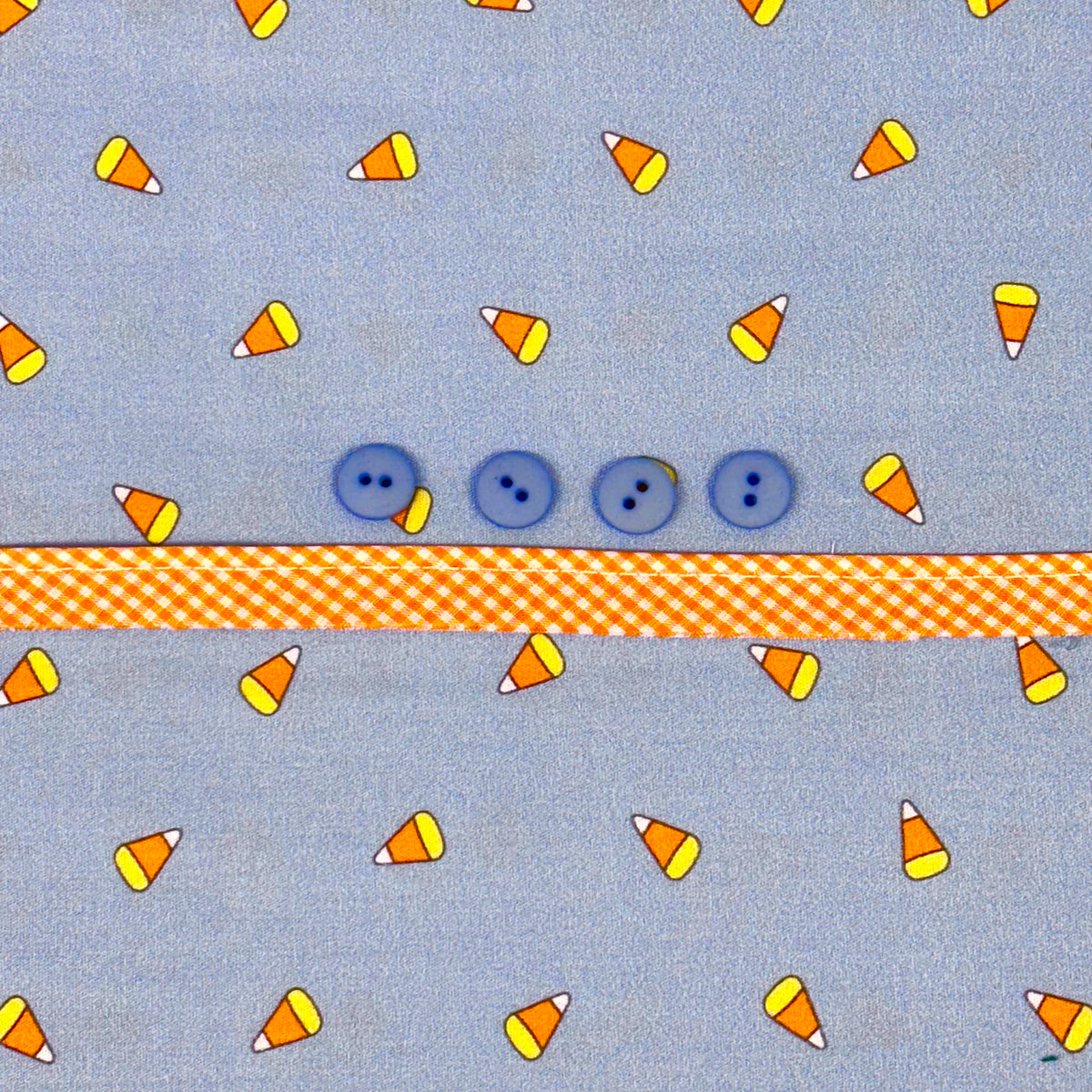 Blue candy corn print fabric with four blue buttons and orange gingham ribbon trim
