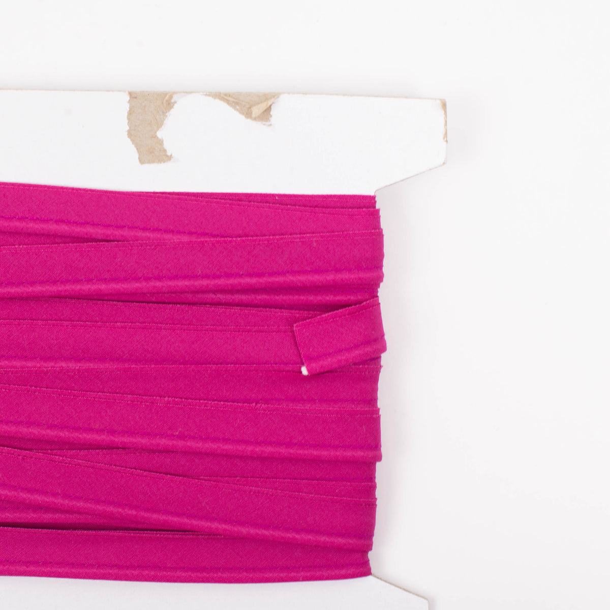Raspberry pink cotton piping trim wound on a cardboard spool, half yard remnant