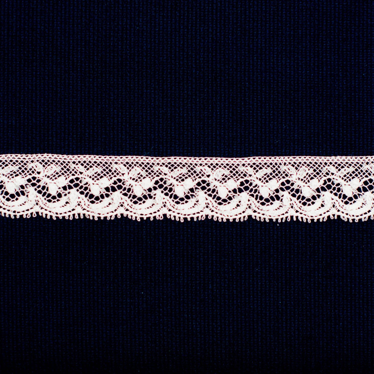 Delicate pink lace edging trim with floral scalloped pattern on navy background
