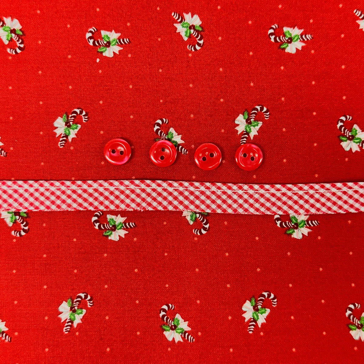 Red candy cane print fabric with red gingham ribbon and four red buttons