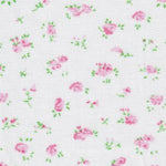 White cotton fabric with scattered small pink rose floral print and green leaves