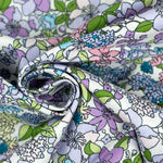 Draped cotton poplin fabric featuring a pastel floral print with purple, blue, pink, and green flowers on white