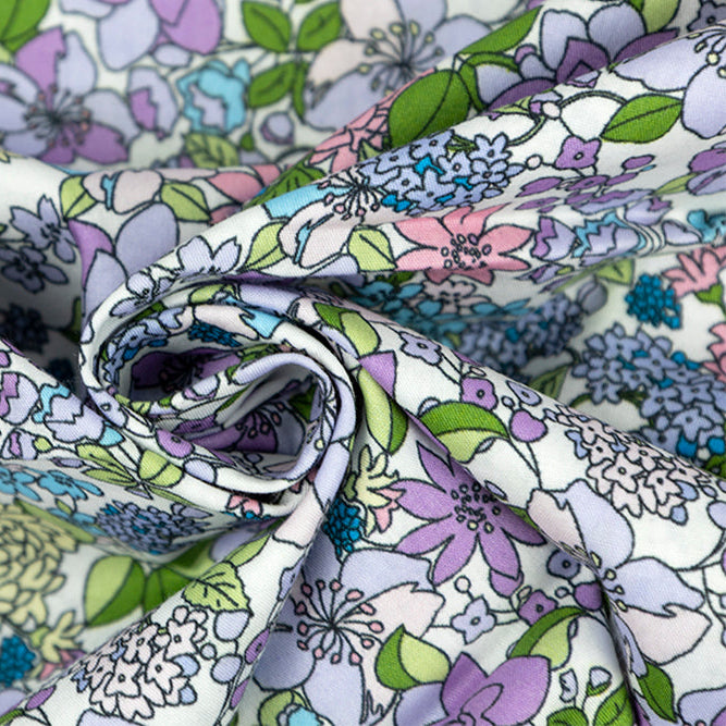 Draped cotton poplin fabric featuring a pastel floral print with purple, blue, pink, and green flowers on white