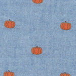 Light blue cotton fabric with small orange pumpkin print pattern scattered evenly