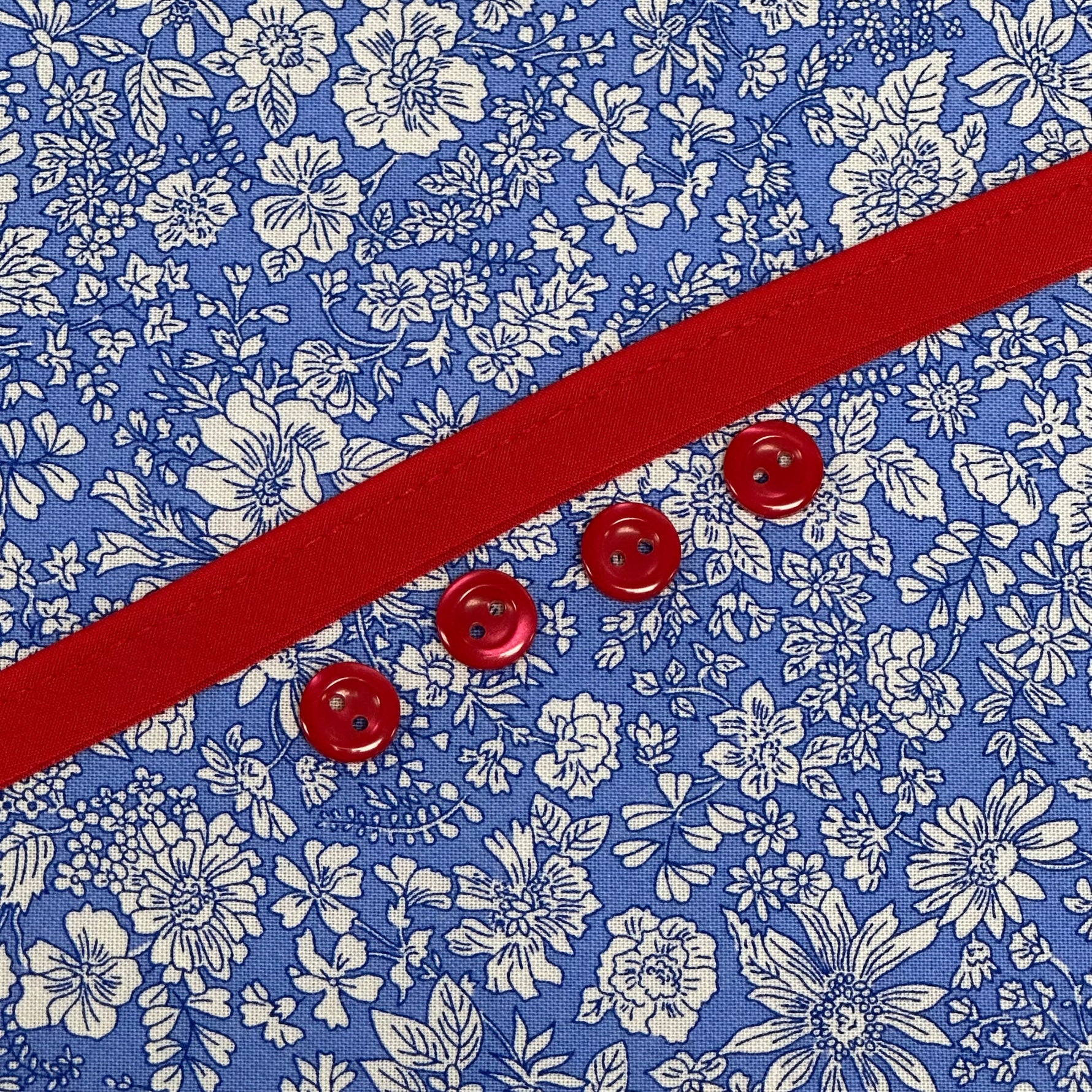 Blue floral fabric with red grosgrain ribbon and four red buttons
