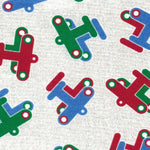 White fabric with tossed red, green, and blue toy airplane prints