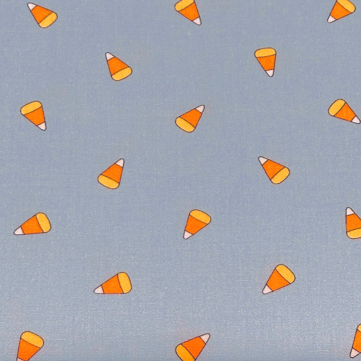Light blue fabric with scattered candy corn print in orange, yellow, and white