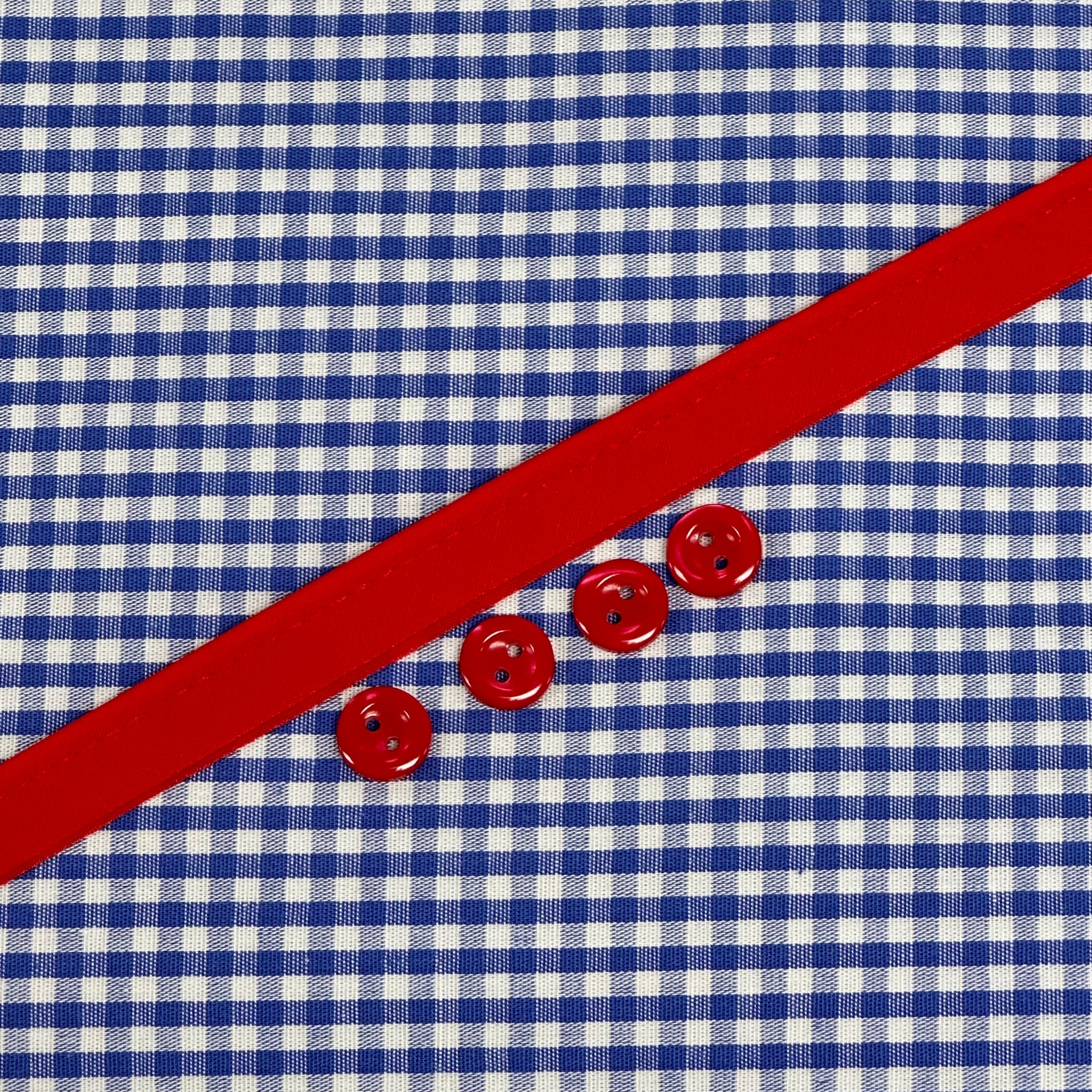 Blue and white gingham fabric with red ribbon trim and three red buttons