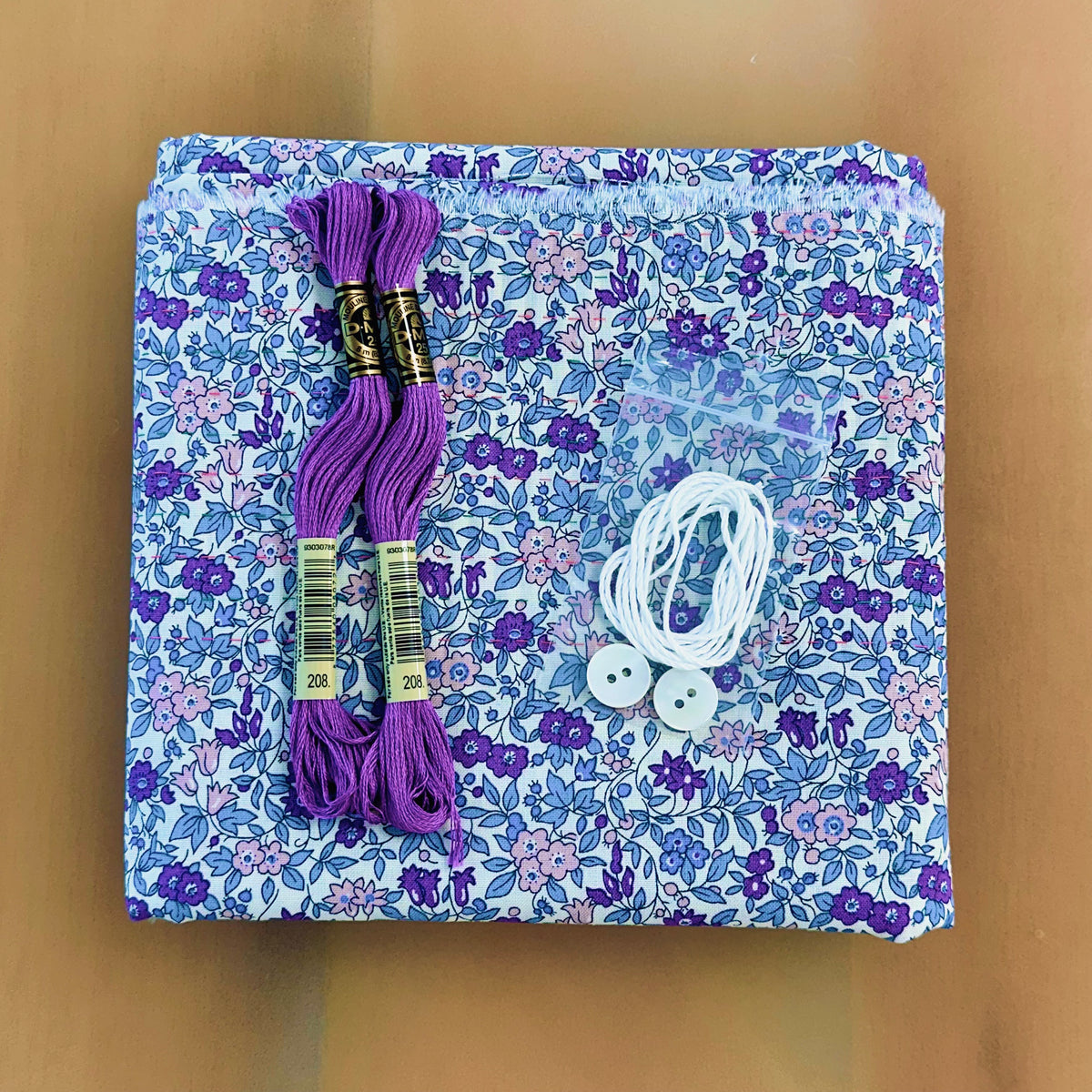 Mary De pre-pleated sewing kit with purple floss, white elastic, buttons, and floral fabric