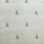 White cotton fabric with small blue dots and scattered green Christmas tree print