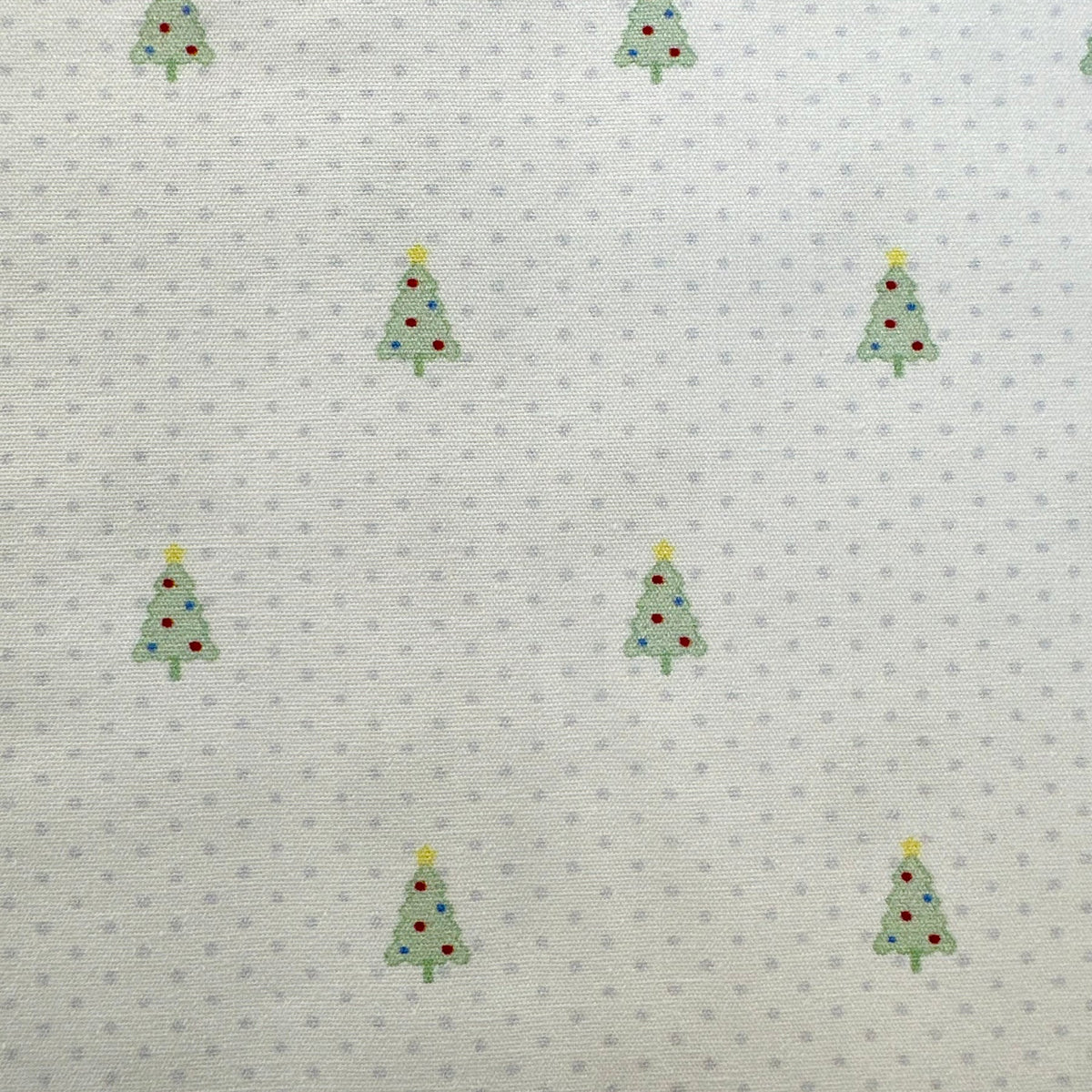White cotton fabric with small blue dots and scattered green Christmas tree print