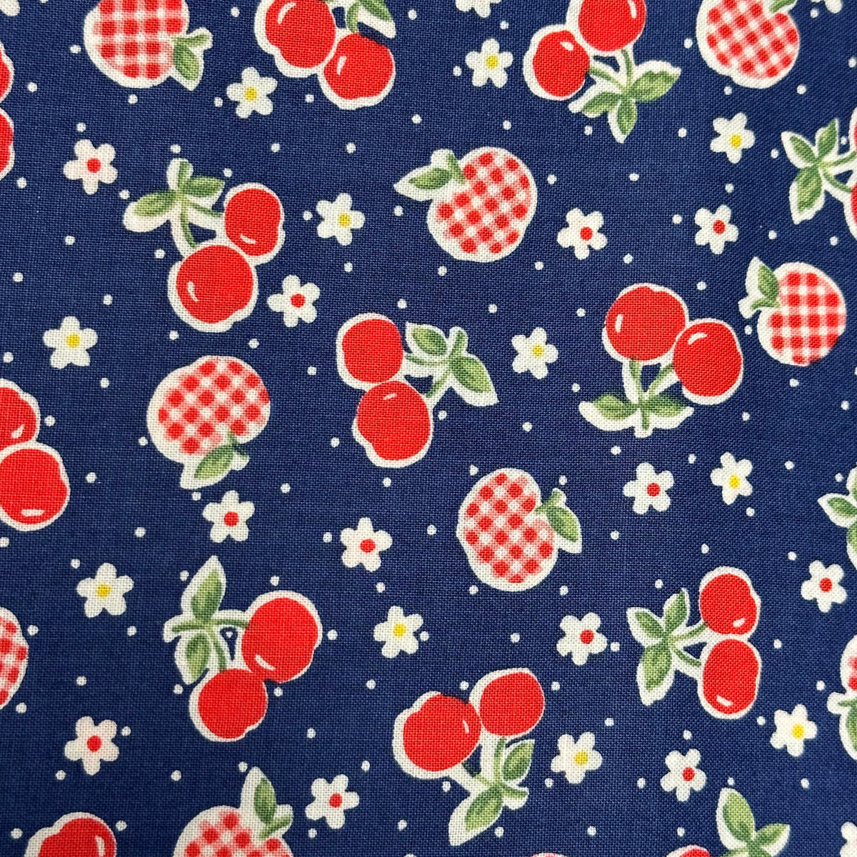 Navy blue quilting cotton fabric with red cherries, gingham apples, and white flowers