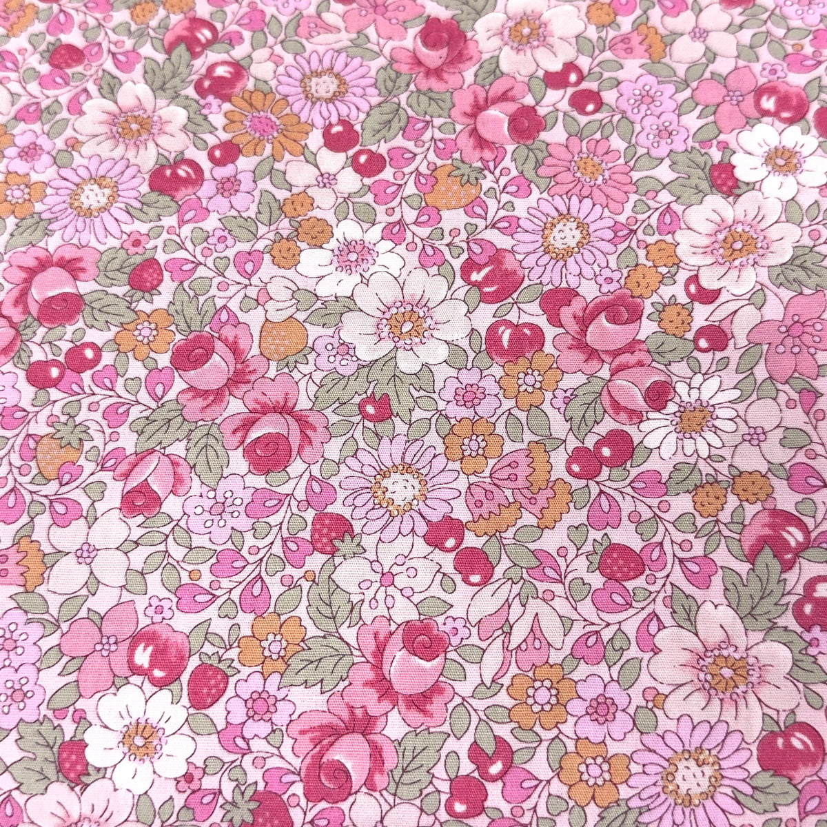 Pink floral cotton fabric with roses, daisies, cherries, and green leaves on white