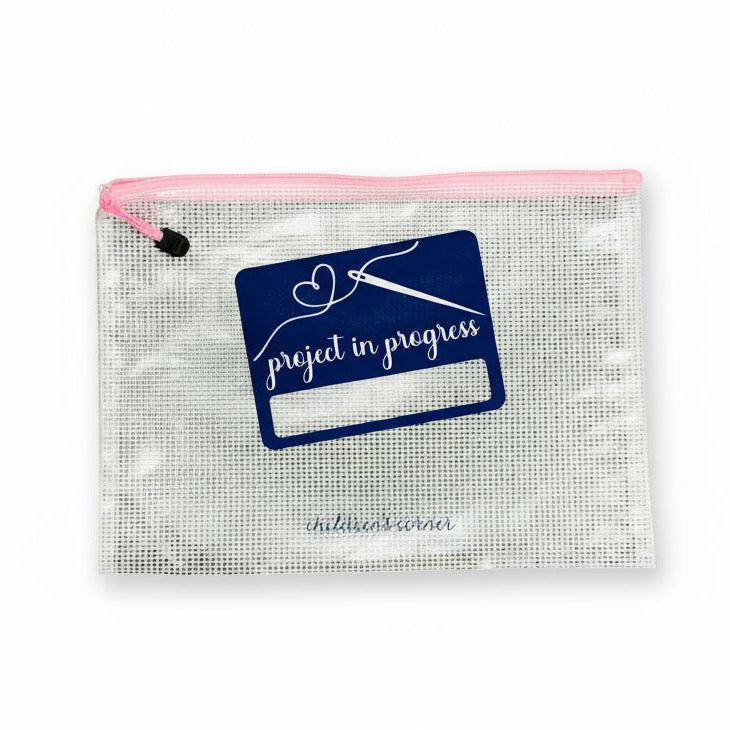 Clear pouch with pink zipper and 'project in progress' logo on a textured surface
