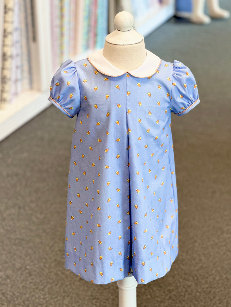 Blue children's dress with candy corn print, peter pan collar, and puff sleeves on mannequin