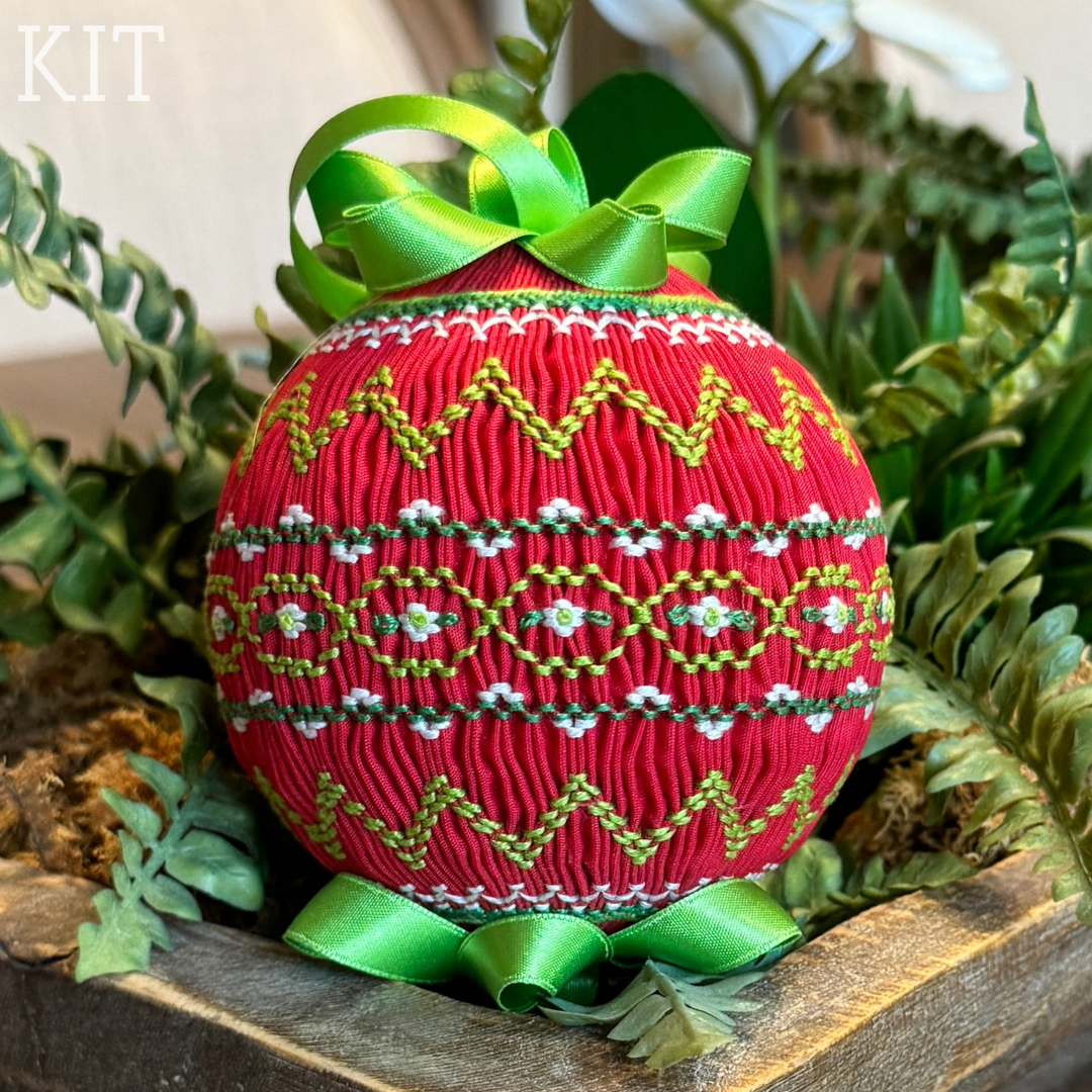 Red smocked Christmas ornament with green geometric embroidery and satin ribbon bow