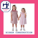 Two girls in smocked bishop dresses, floral and pink, holding hands