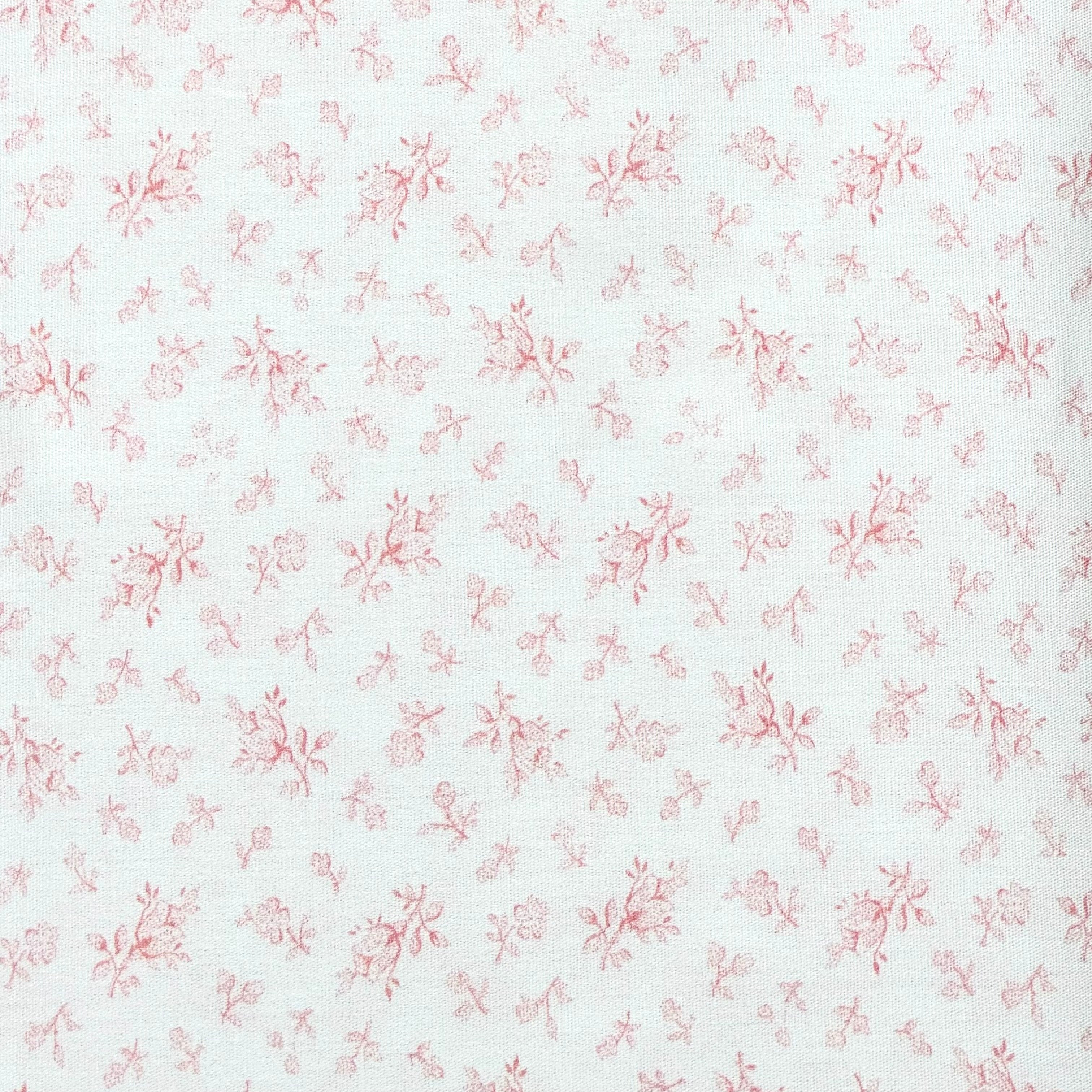White cotton fabric with scattered small pink floral ditsy print pattern