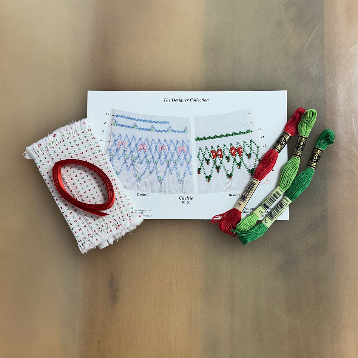 Chelsie smocking kit with red and green DMC floss, dotted fabric, and pattern card