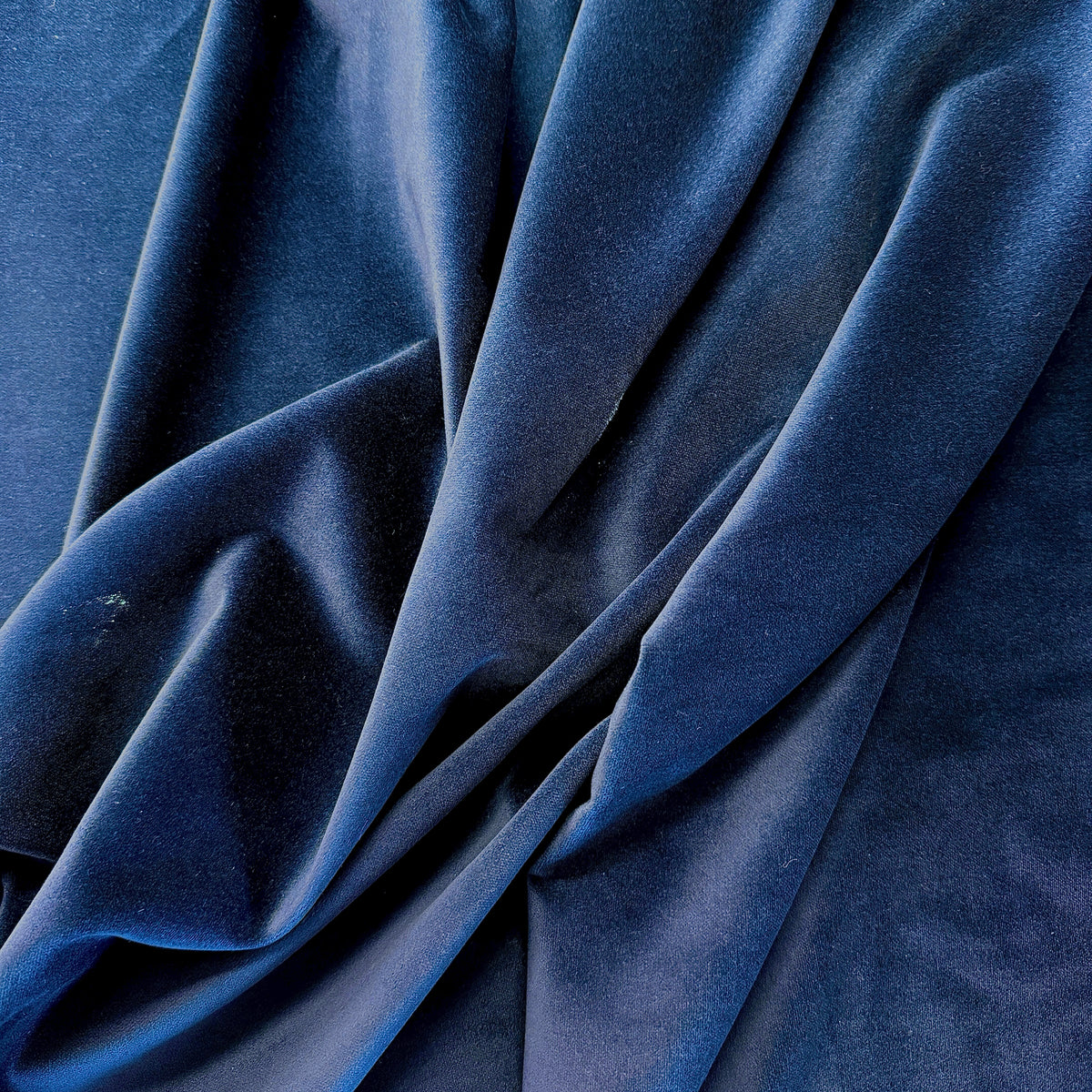 Navy blue velveteen fabric draped in soft folds showing rich texture and sheen
