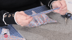 Hands attaching blue bias tape to floral fabric on a cutting mat