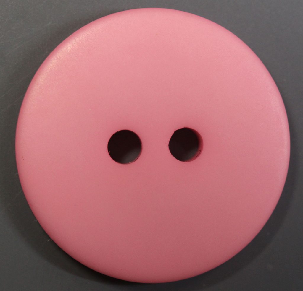 Large round pink plastic button with two holes on gray background