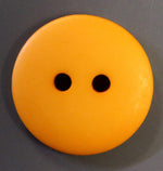 Large round orange plastic button with two holes on gray background