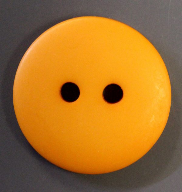 Large round orange plastic button with two holes on gray background