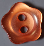 Amber brown two-hole plastic button with wavy flower-shaped scalloped edge