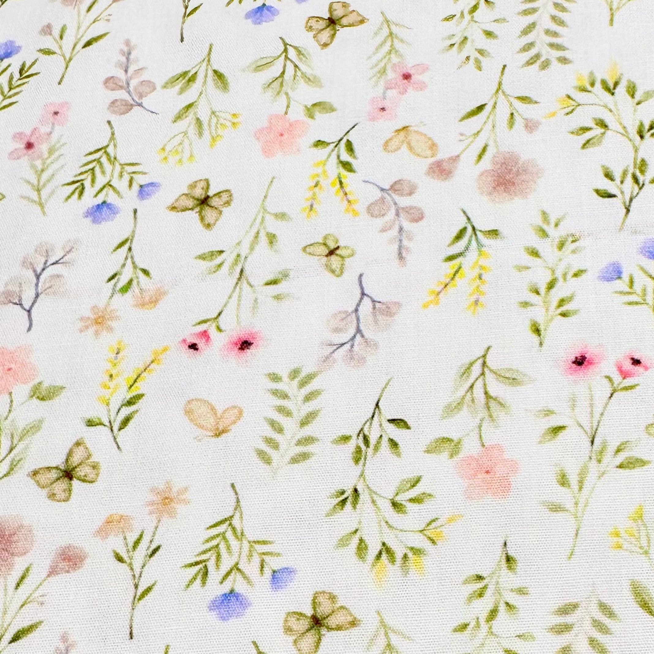 White cotton fabric with watercolor floral print featuring butterflies, pastel flowers, and green leaves