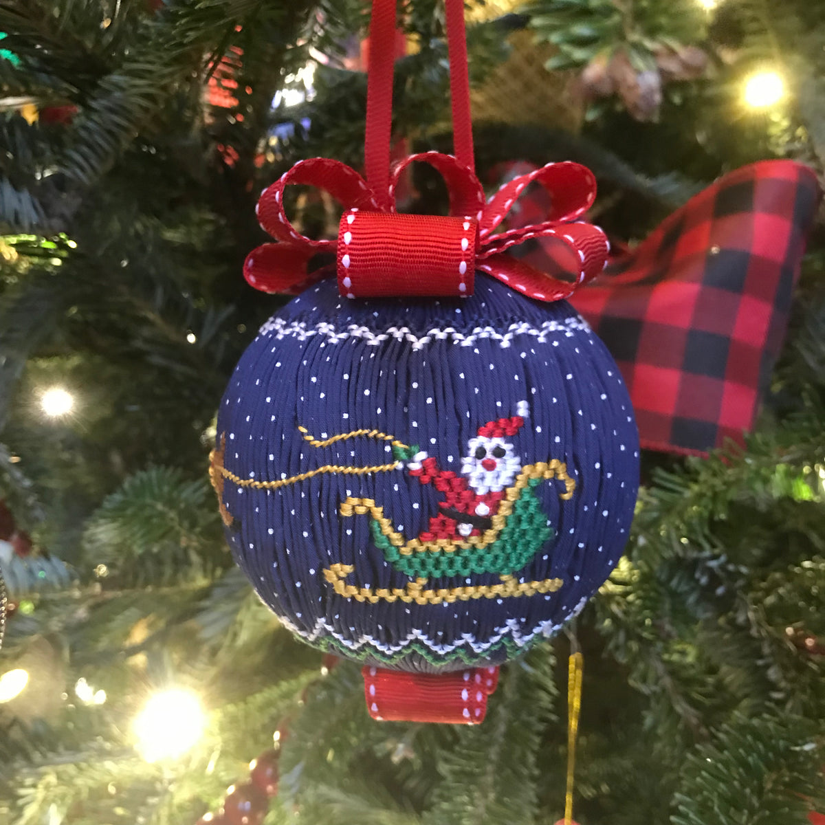 Navy blue smocked Christmas ornament with Santa sleigh design and red ribbon bow