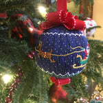 Navy blue smocked Christmas ornament with Santa sleigh reindeer scene and red ribbon bow