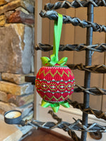 Red smocked Christmas ornament with green embroidery, ribbon bow, hanging on iron stand