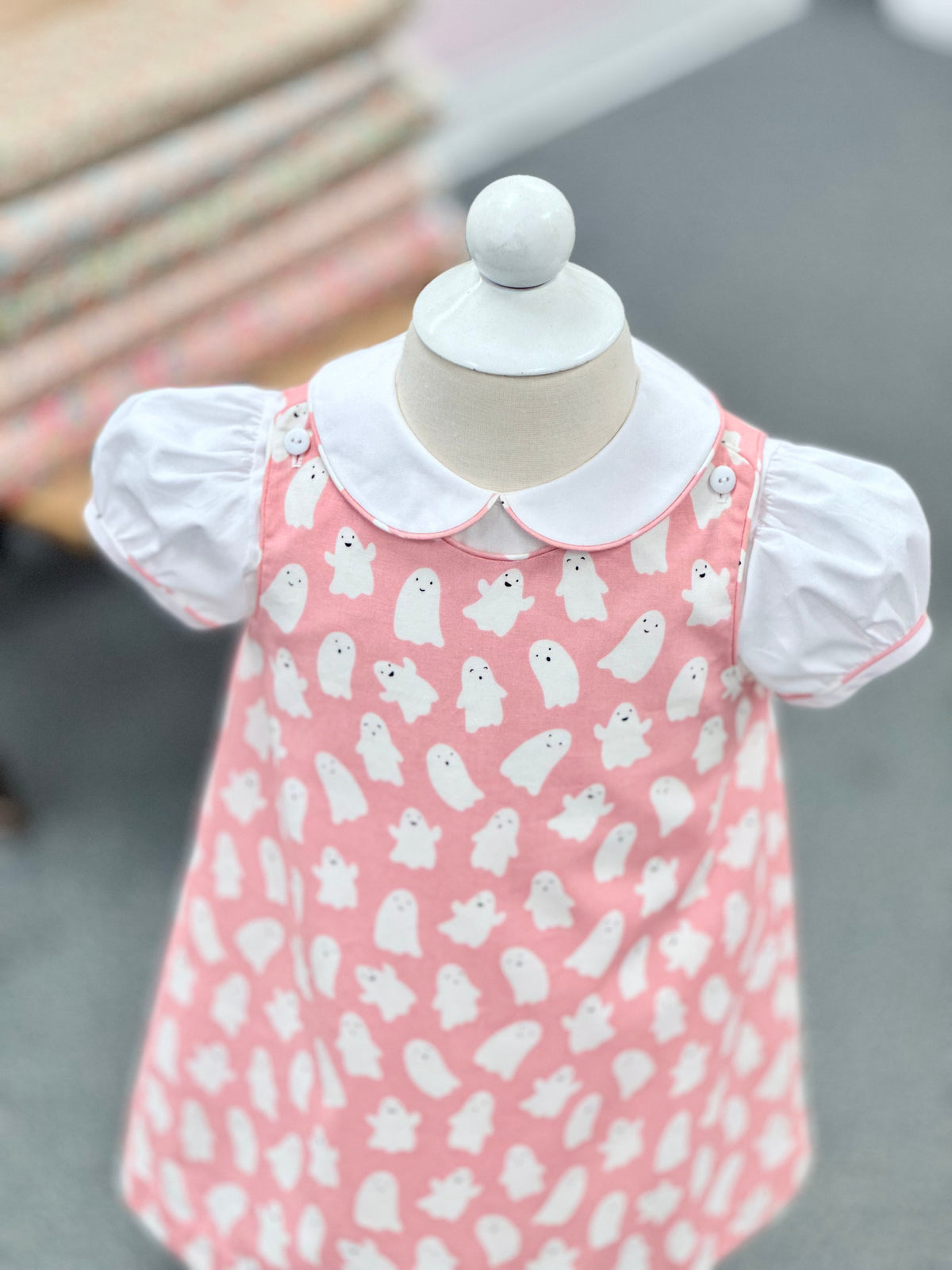 Pink baby dress with white ghost print and white Peter Pan collar on mannequin