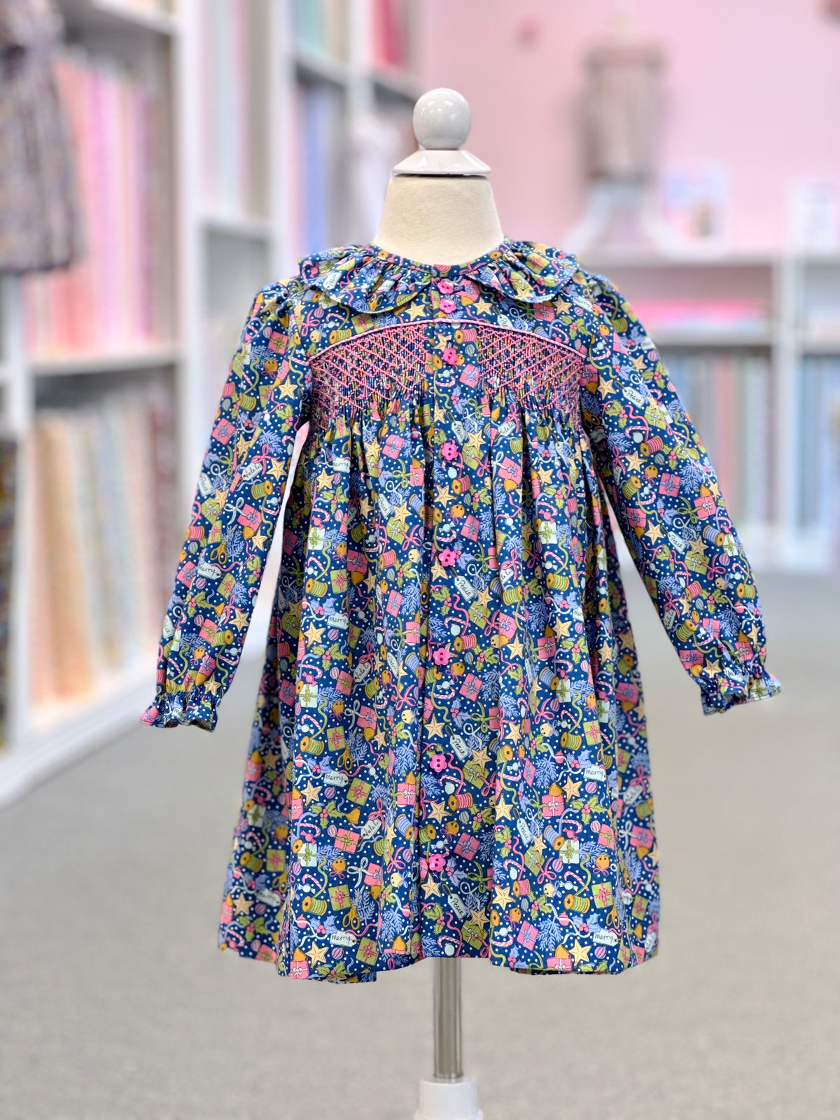 Navy floral smocked long-sleeve girls dress with ruffled collar on mannequin