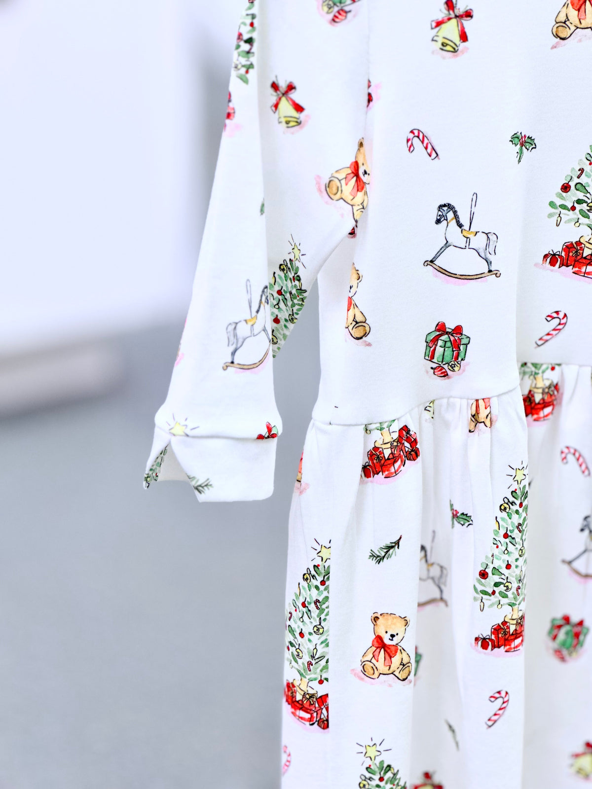 White knit fabric with festive Christmas print featuring teddy bears, rocking horses, and candy canes